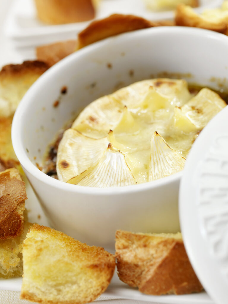 Baked brie in a brie baker with toasted french bread