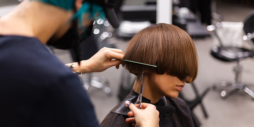 professional girl hairdresser makes client haircut girl is sitting mask beauty salon