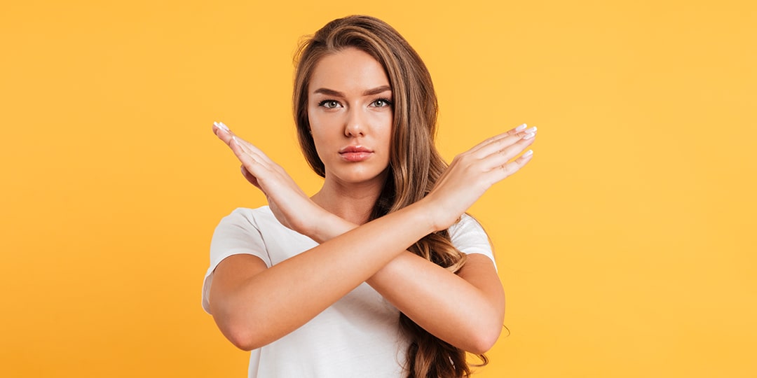 serious caucasian woman standing near copyspace showing stop gesture