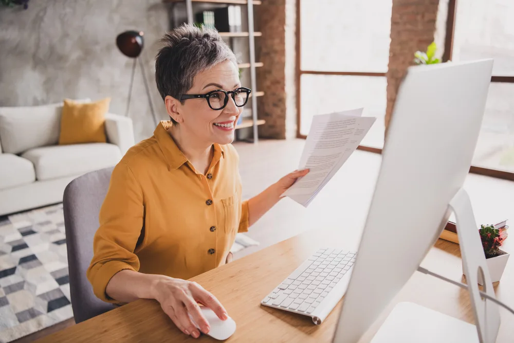 A middle aged woman working on her laptop at home conducting online research for clients